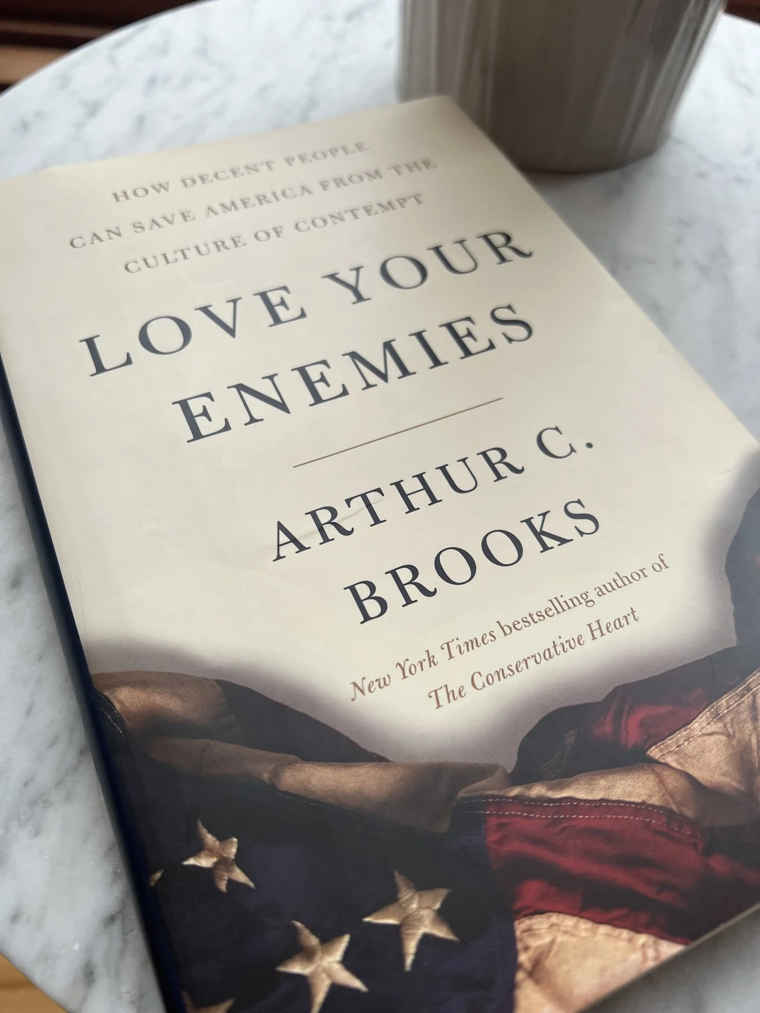 A copy of Love Your Enemies by Arthur C. Brooks on a table.