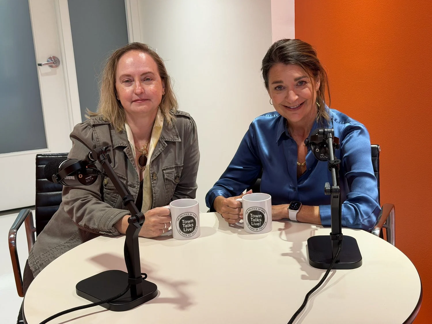 Joan VonDras and a guest sitting at a table with microphones for a Town Talks Live conversation.